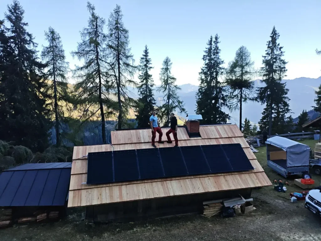 Michi und Andi auf dem Scheunendach mit PV-Modulen in den Alpen
